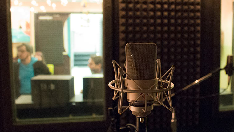 Microphone in recording studio with students in background.