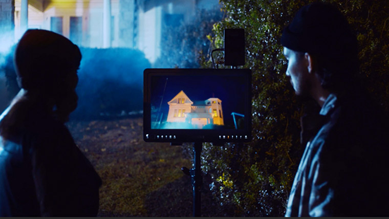 Two filmmakers watching a scene on video village as it's filmed.