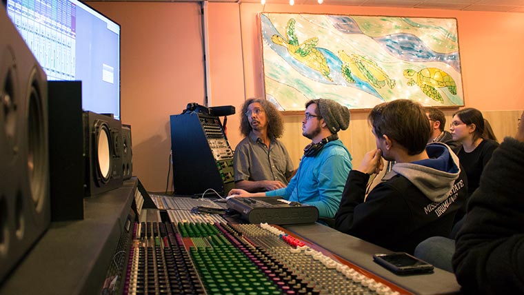 Professor helping students edit audio.